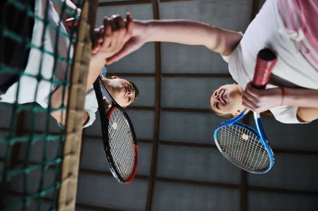 tennis players shaking hands over net